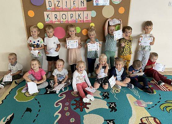 dzieci stoją i trzynmają dyplomy