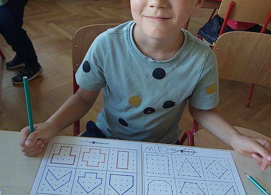 chłopiec siedzi przy stoliku i koduje