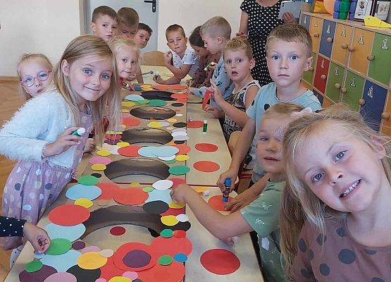 dzieci oklejają kolorowymi kropkami makietę