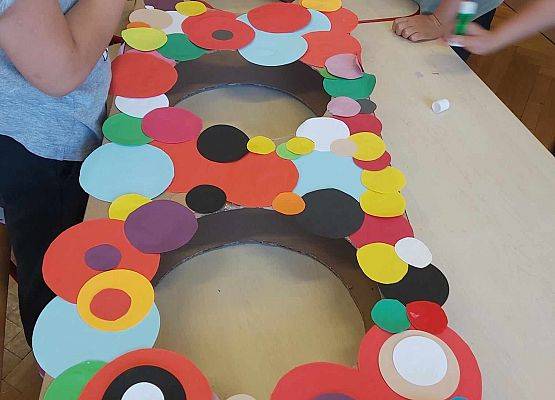 dzieci oklejają kropkami makietę