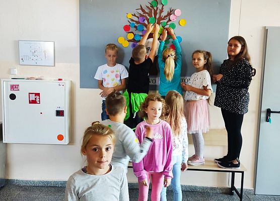 uczniowie wieszają kropki na drzewie talentów