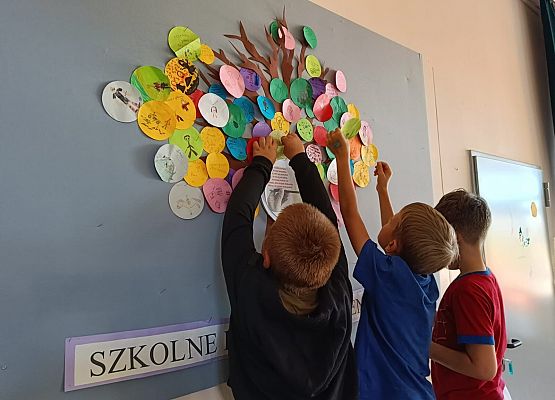 uczniowie wieszają kropki na drzewie talentów