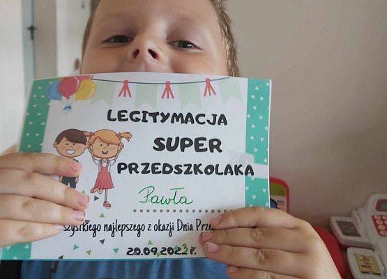 chłopiec pokazuje legitymację super przedszkolaka