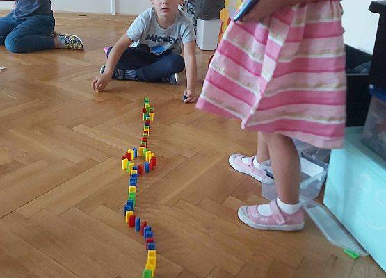 chłopiec siedzi na podłodze i układa klocki