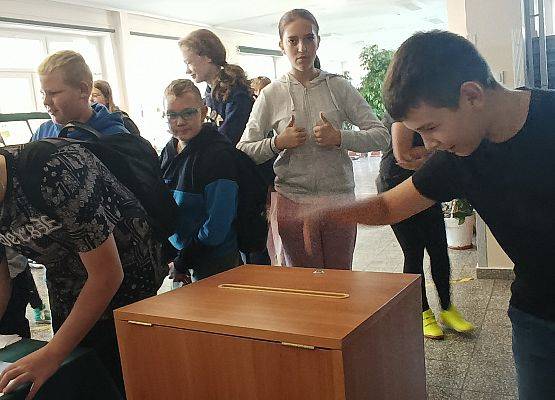 uczniowie oddają swoje głosy wrzucając karty do urny