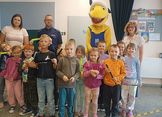 zdjęcie grupowe dzieci z panią wicedyrektor, nauczycielką, policjantem i Mrówką