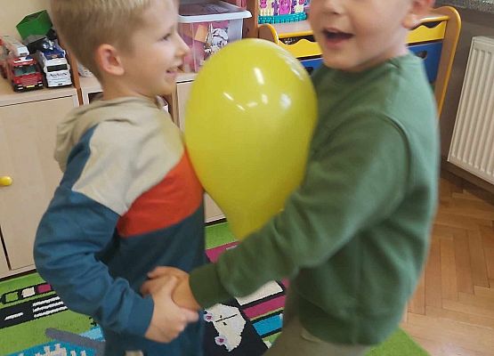 dwaj chłopcy tańczą z balonem