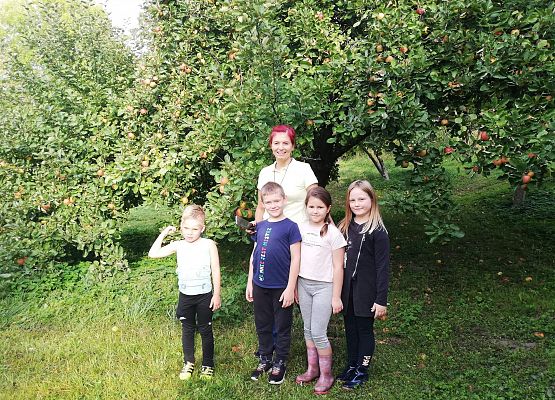 nauczycielka z uczniami na tle drzewa