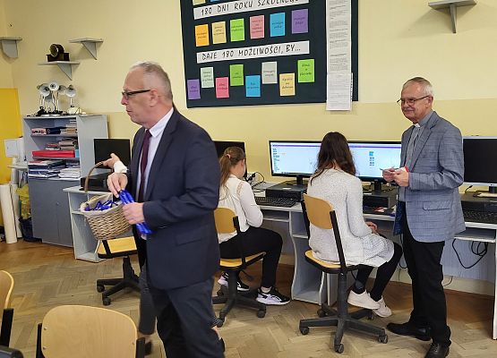 ksiądz, dyrektor i przedstawiciel rady rodziców wręczają upominki uczniom