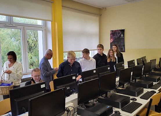 ksiądz, dyrektor i przedstawiciel rady rodziców wręczają upominki uczniom