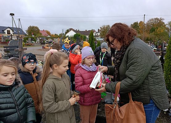 nauczycielka zapala znicz, obok uczniowie