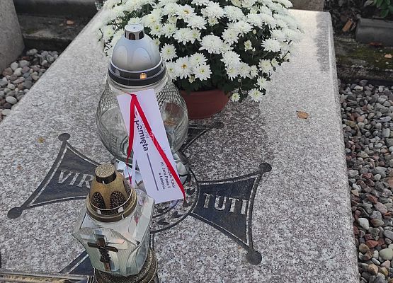 grób, na którym stoją znicze i kwiaty