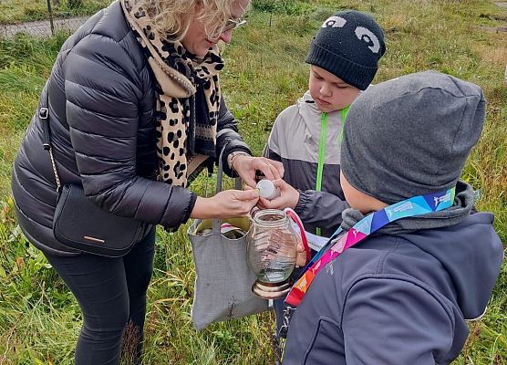 nauczycielka zapala znicz, obok uczniowie