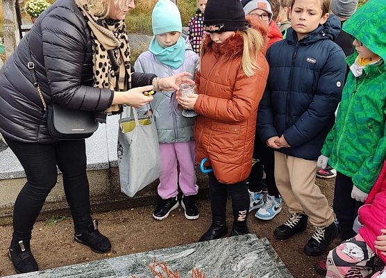 nauczycielka zapala znicz, obok uczniowie