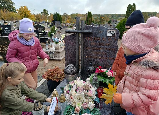 uczennica kładzie znicz na grobie