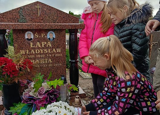 uczennica kładzie znicz na grobie