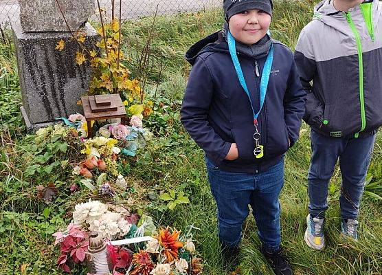 uczniowie stoją przy grobie jeńców wojennych