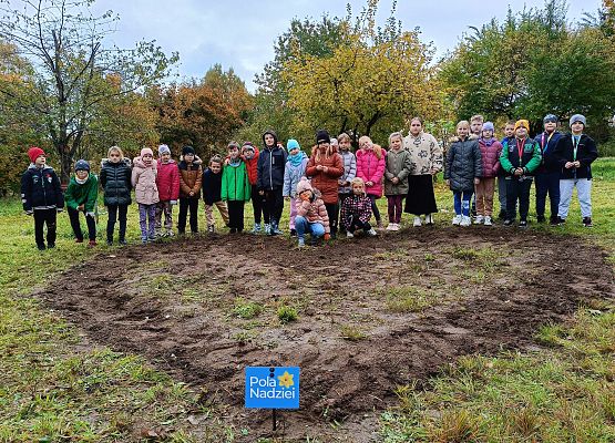 uczniowie na tle serca, w którym posadzili cebulki żonkili