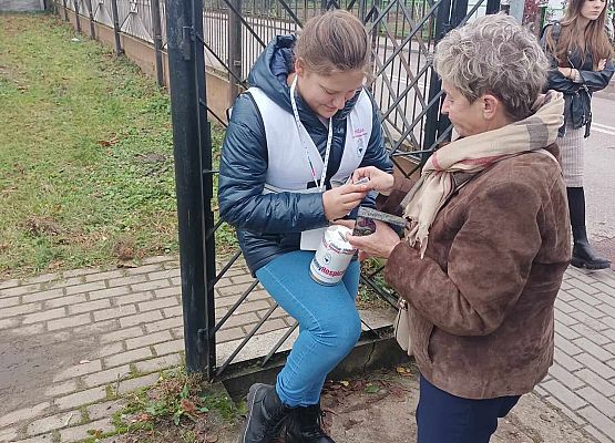 kobieta wrzuca darowiznę do puszki