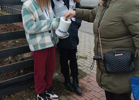 kobieta wrzuca darowiznę do puszki