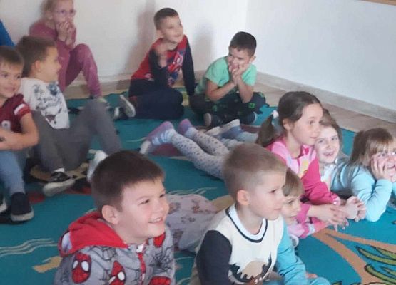 dzieci siedzą na dywanie i oglądają teatrzyk