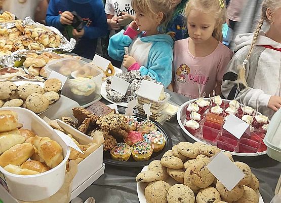 dzieci stoją przy stole ze słodkościami