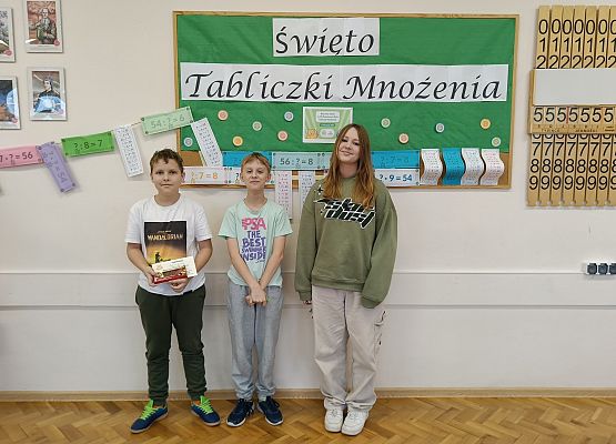 uczniowie stoją  na tle gazetki szkolnej