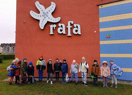 uczniowie stoją przed budynkiem pływalni