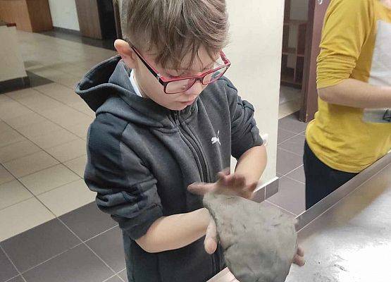 chłopiec obrabia masę glinianą
