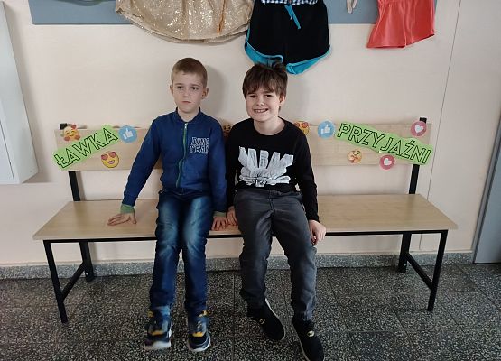 dwaj chłopcy siedzą na ławce życzliwości