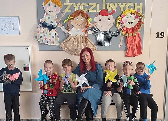 dzieci z nauczycielką siedzą na ławce