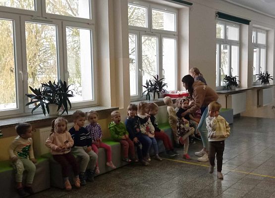 przedszkolaki siedzą w holu