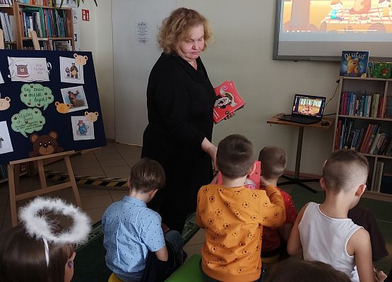 bibliotekarka wręcza dzieciom książki