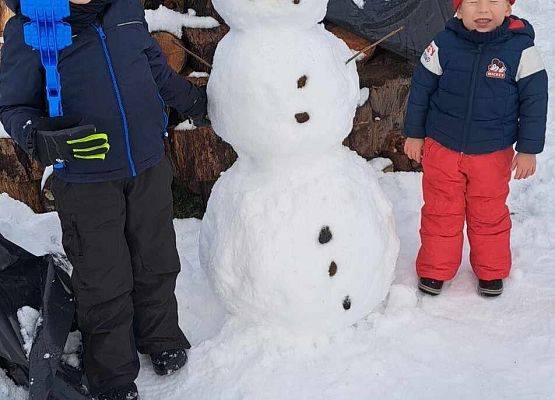 dwaj chłopcy stoją obok bałwana