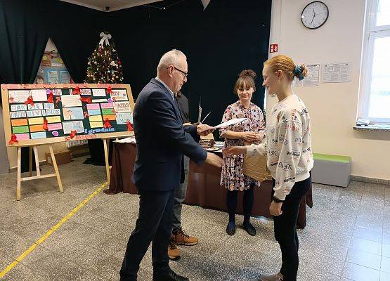 dyrektor wręcza uczennicy nagrodę