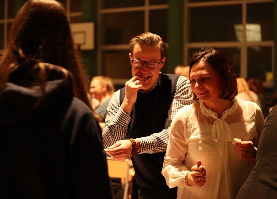 goście składają sobie życzenia i łamią się opłatkiem