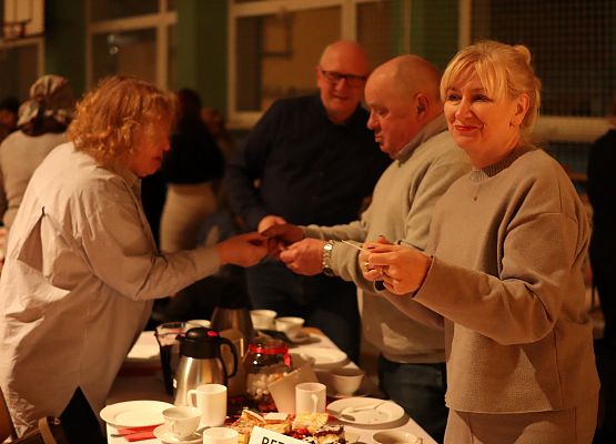 goście składają sobie życzenia i łamią się opłatkiem