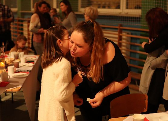 goście składają sobie życzenia i łamią się opłatkiem