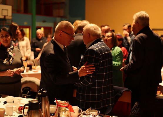 goście składają sobie życzenia i łamią się opłatkiem