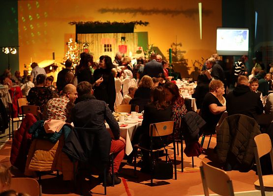 goście składają sobie życzenia i łamią się opłatkiem