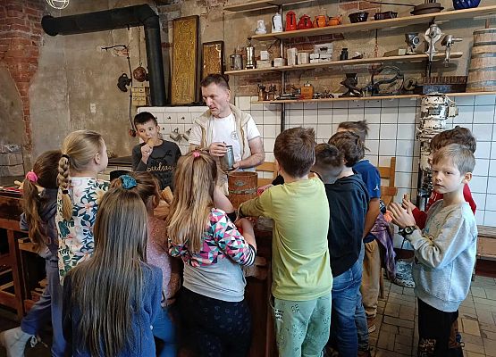 piekarz prezentuje dzieciom narzędzia piekarnicze