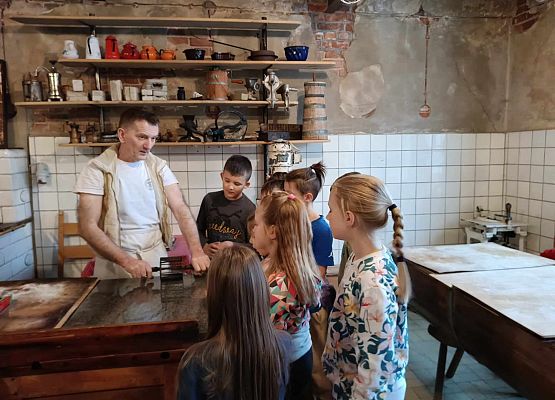 piekarz prezentuje dzieciom narzędzia piekarnicze