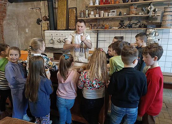 piekarz prezentuje dzieciom narzędzia piekarnicze