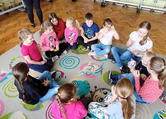 dzieci siedzą na dywanie