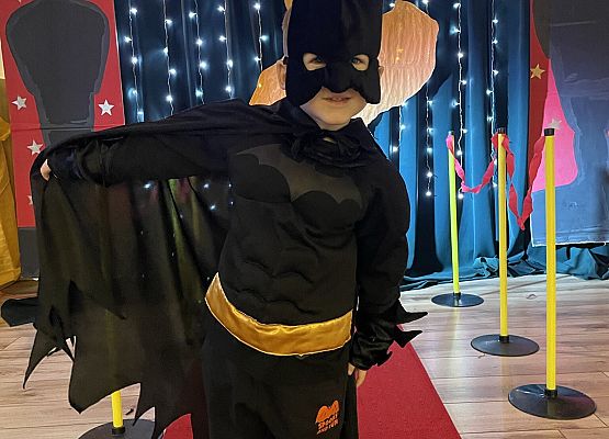 chłopiec w stroju Batmana stoi na czerwonym dywanie
