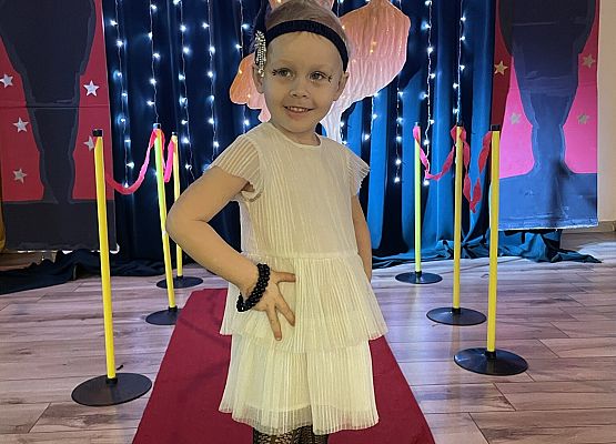 dziewczynka stoi na czerwonym dywanie