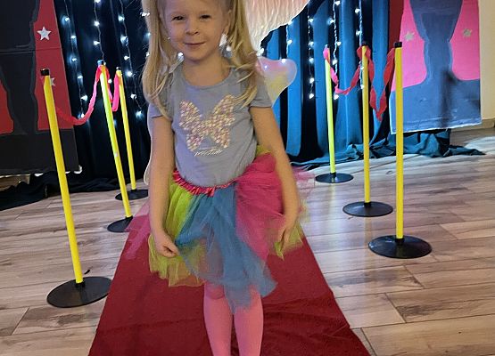 dziewczynka w stroju motyla stoi na czerwonym dywanie