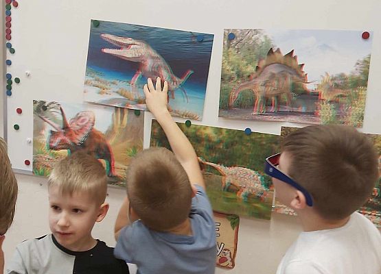 dzieci oglądają ilustracje dinozaurów