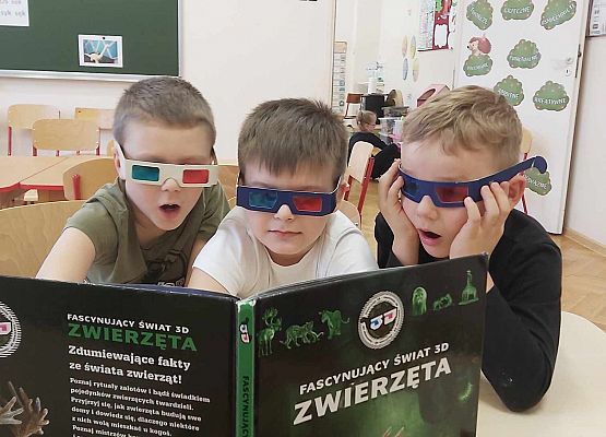chłopcy w okularach 3D oglądają książkę