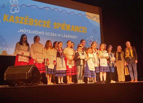 uczniowie w strojach kaszubskich stoją na scenie